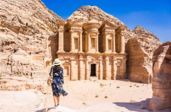 Asian young woman in colorful dress and hat enjoying at The Monastery, Petra's largest monument, UNESCO World Heritage Site, Jordan.