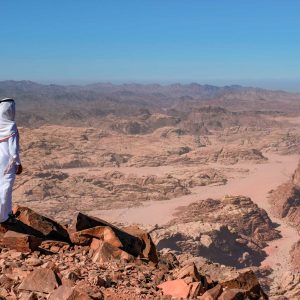 A bedouin standing in the summit Jabal Umm ad Dami, the highest mountain in Jordan. Panoramic landscape of the valleys and hills in the remote region of Jordan, near to the border with Saudi Arabia.