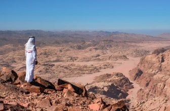 A bedouin standing in the summit Jabal Umm ad Dami, the highest mountain in Jordan. Panoramic landscape of the valleys and hills in the remote region of Jordan, near to the border with Saudi Arabia.